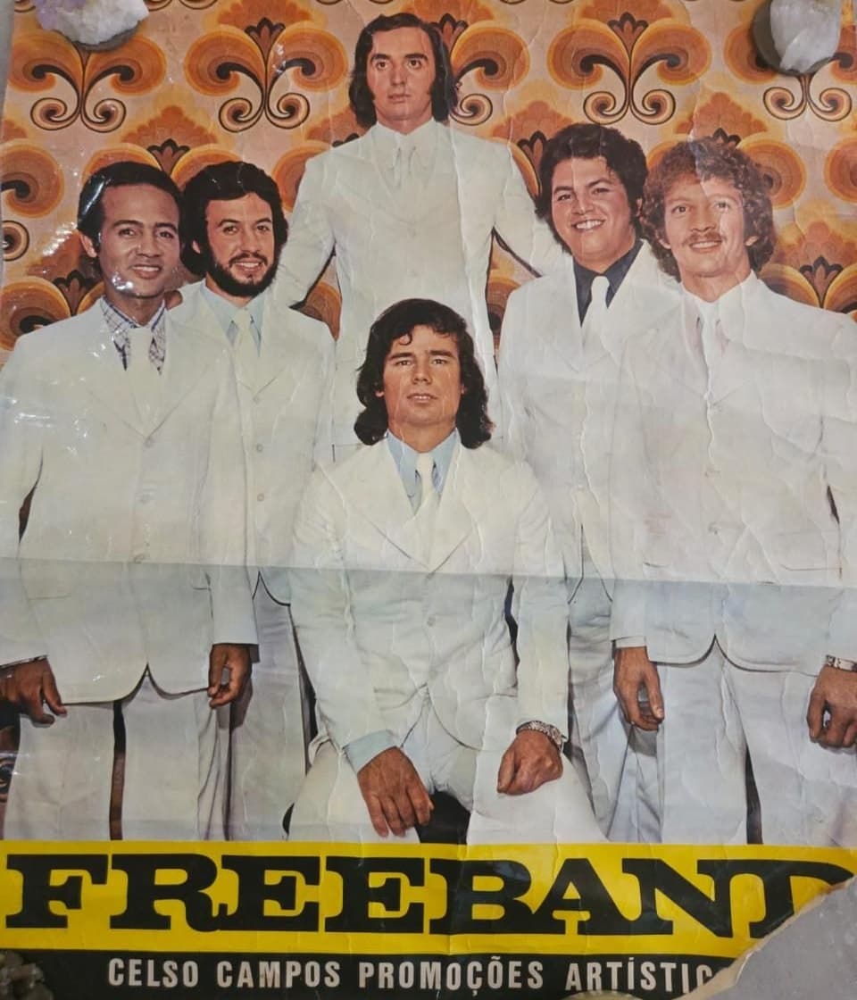 Cartaz de divulgação antigo: seis integrantes de terno branco sobre um fundo estampado laranja, com a faixa FREEBAND e o crédito Celso Campos Promoções Artísticas