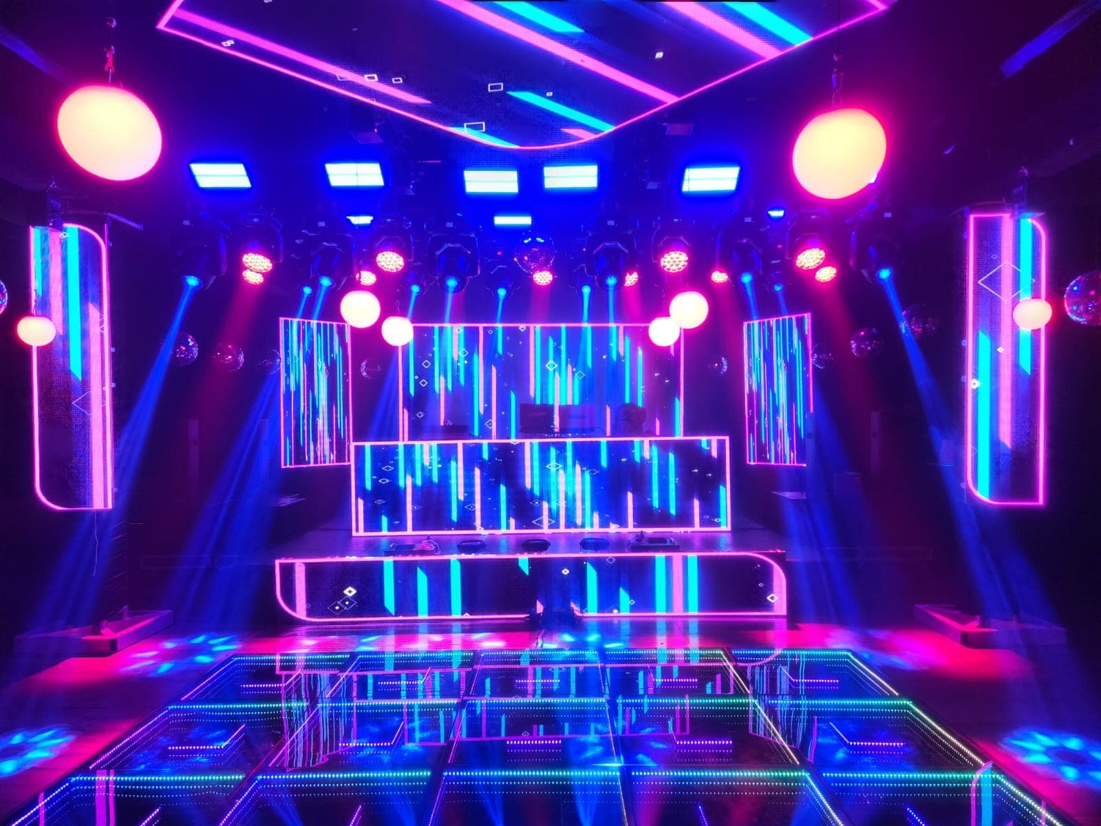Estrutura de boate montada com pista de LED, painéis e iluminação em neon rosa e azul