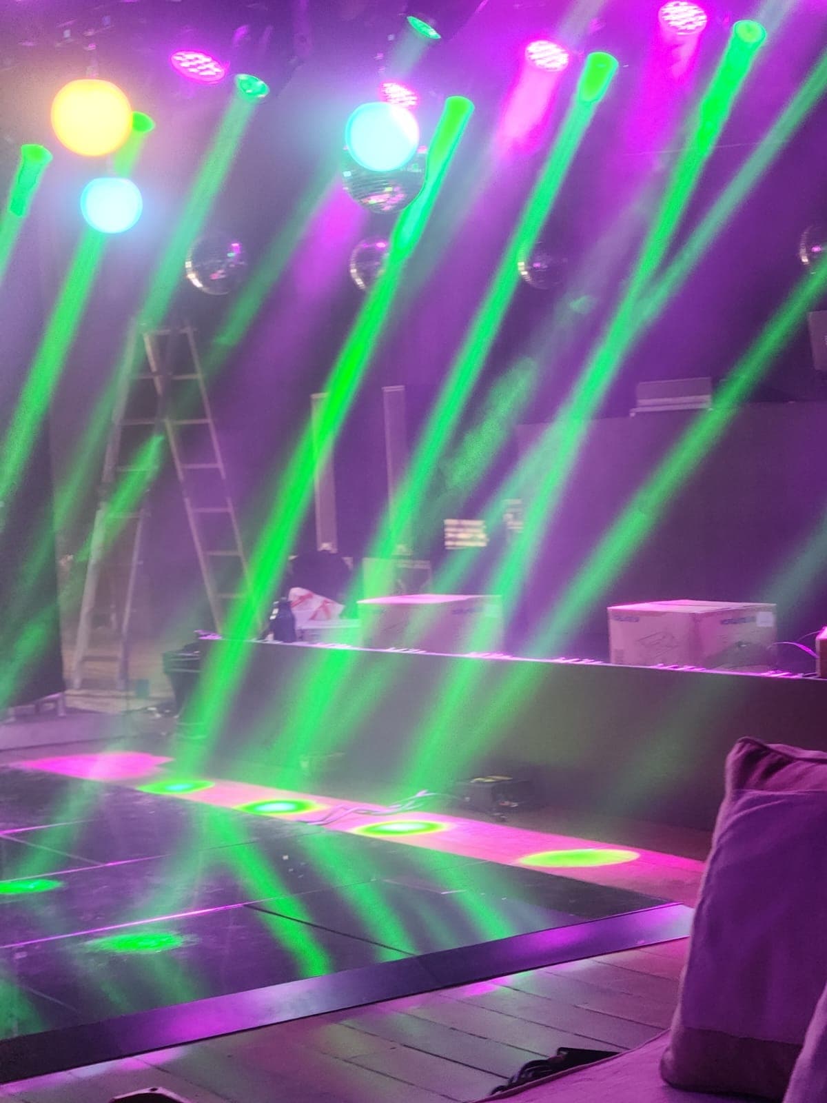 Feixes verdes da iluminação robotizada cruzando a pista de LED durante o ajuste