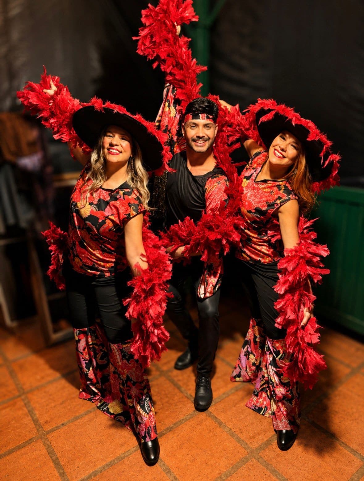 Bailarinos em figurino vermelho com plumas e chapéus